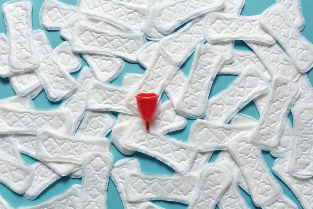 Top view of menstrual products including pads and cup on a blue background.